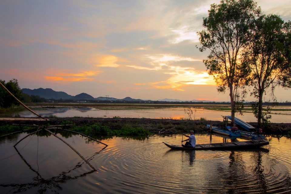 A tranquil boat ride on a river at sunset in An Giang, Vietnam.