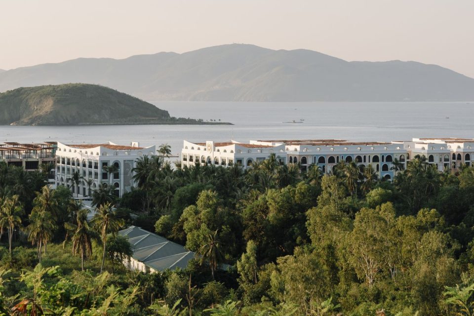 A serene view of a coastal resort surrounded by lush greenery and ocean.