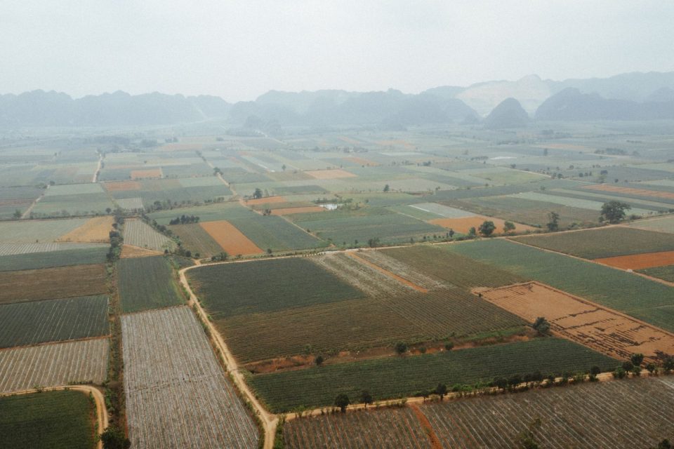 Aerial shot showcasing vast rural farmlands and mountains in the background.