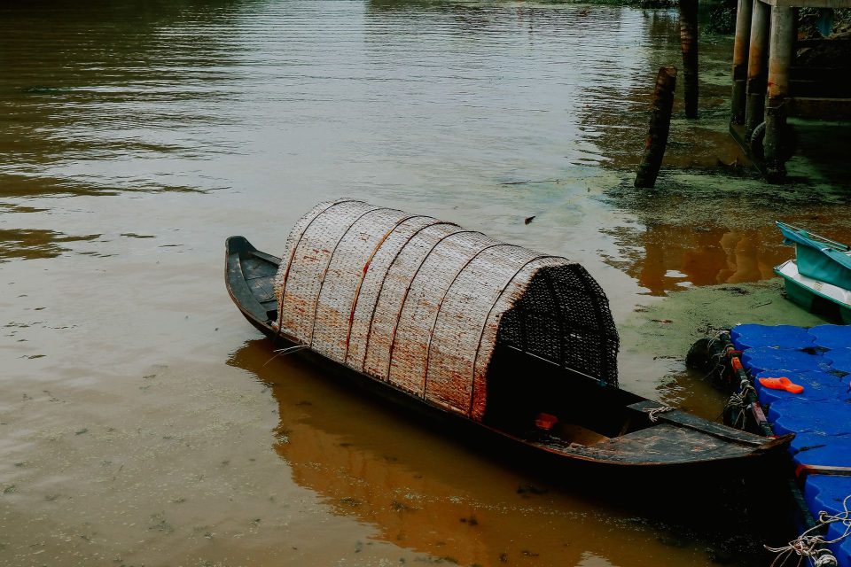 A serene view of a traditional wooden boat moored by the shore in Ben Tre, Vietnam.