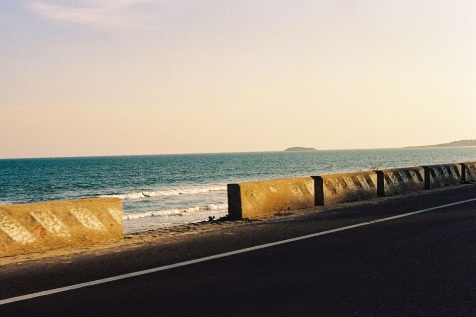 A serene coastal road and ocean view in Phan Thiết, Việt Nam during sunset.