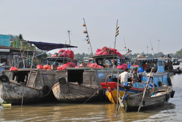 Vibrant scene of boats at a Mekong Delta floating market, featuring colorful goods and lively activity.