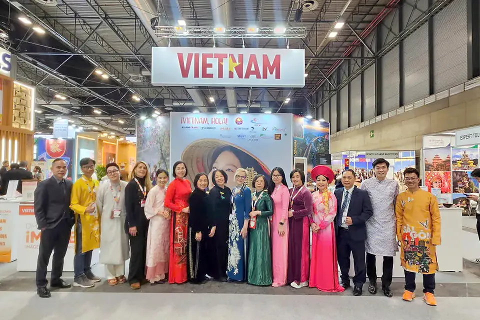 Đoàn doanh nghiệp Việt Nam mặc áo dài chụp ảnh chung dưới bảng hiệu VIETNAM tại gian hàng FITUR 2026 ở Madrid