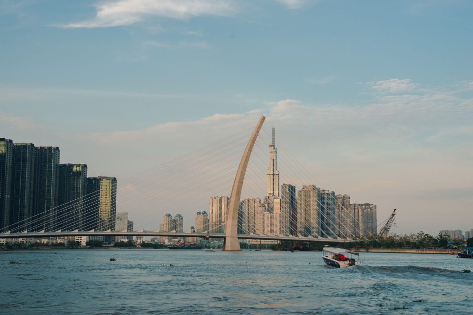 View of modern Ho Chi Minh City skyline featuring a prominent bridge and river scene.