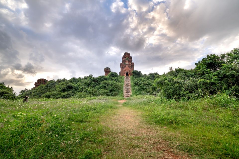 Explore tranquil ancient temple ruins surrounded by lush greenery and dramatic skies.