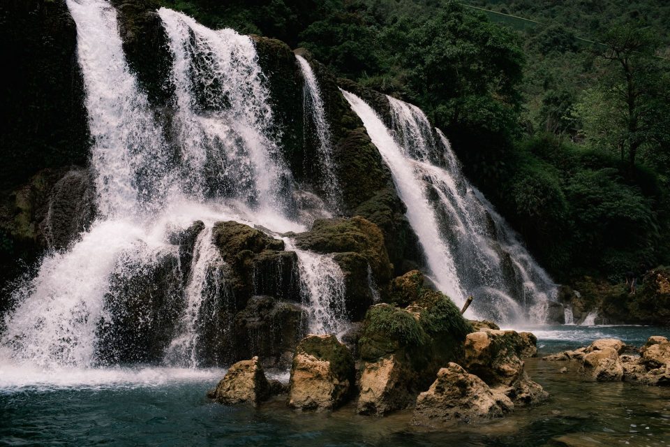 A breathtaking view of a cascading waterfall in Cao Bằng, Vietnam, surrounded by lush greenery.