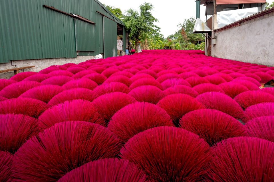 Brightly colored incense sticks drying outdoors in Vietnam's rural village setting.