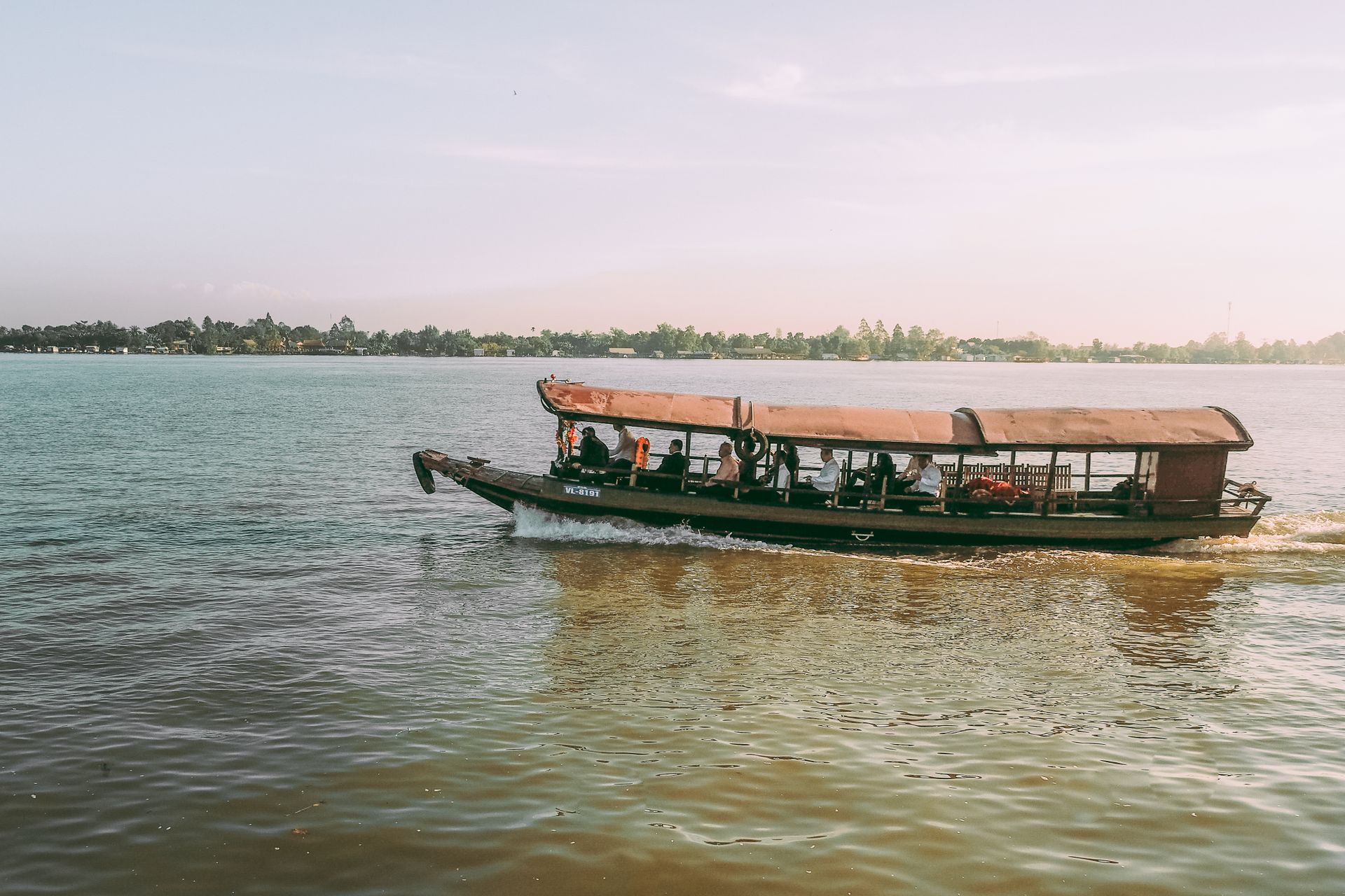Scenic view of a traditional boat cruising on the Mekong River in Vinh Long, Vietnam.