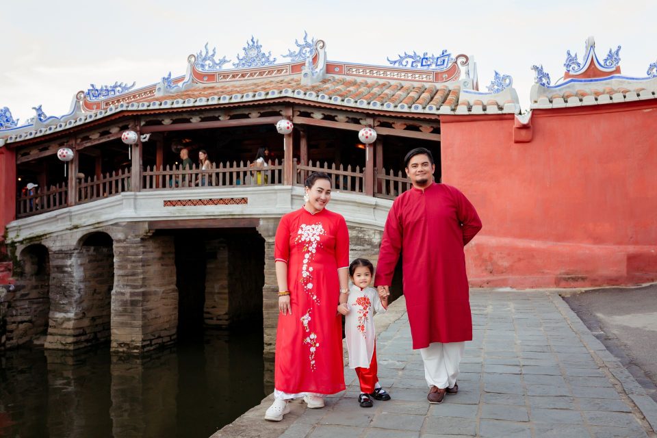 A family in traditional Vietnamese attire poses by the iconic Japanese Covered Bridge in Hội An.
