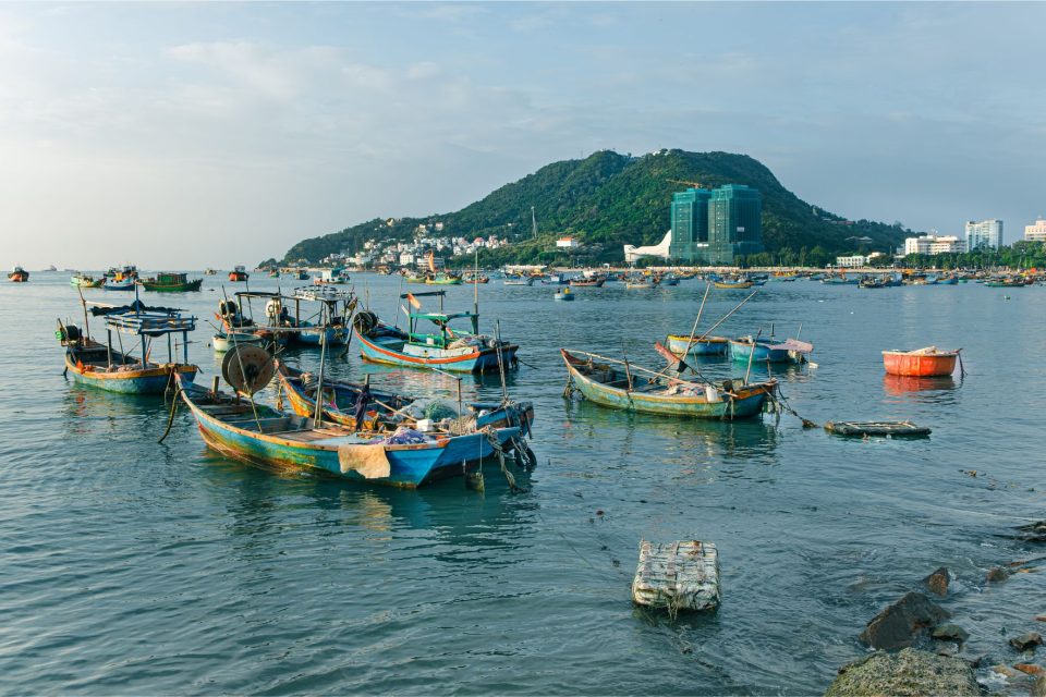 Scenic view of traditional fishing boats on the sea in Ho Chi Minh City, Vietnam with a lush green hill background.