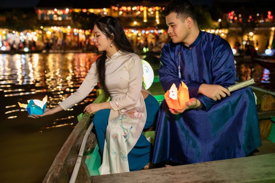 Couple releases lanterns in Hoi An, Vietnam, at night along the river.