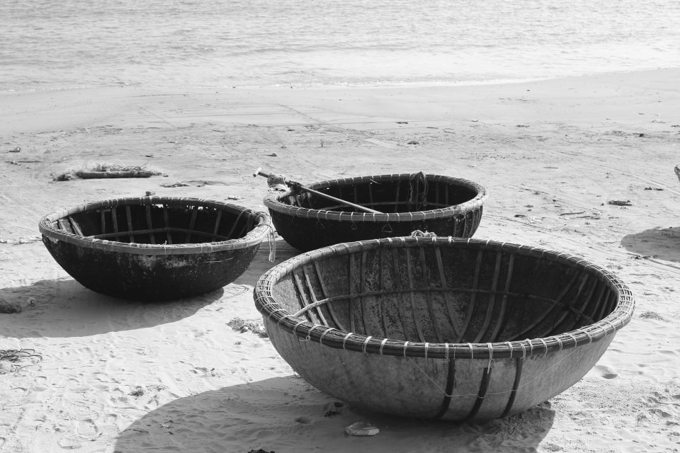 Black and white photo of traditional Vietnamese basket boats on a sandy beach, capturing cultural and natural beauty.