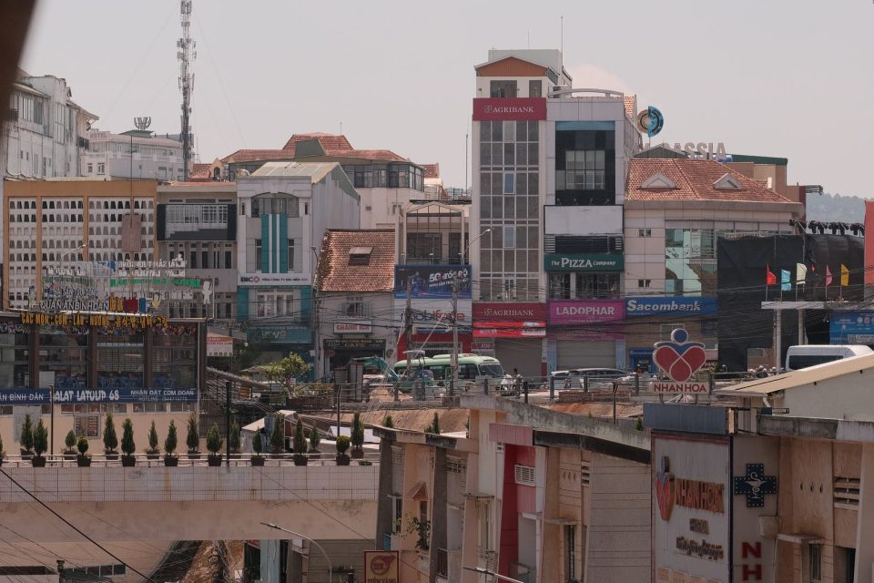 View of bustling Dalat city center with various commercial buildings and signage.